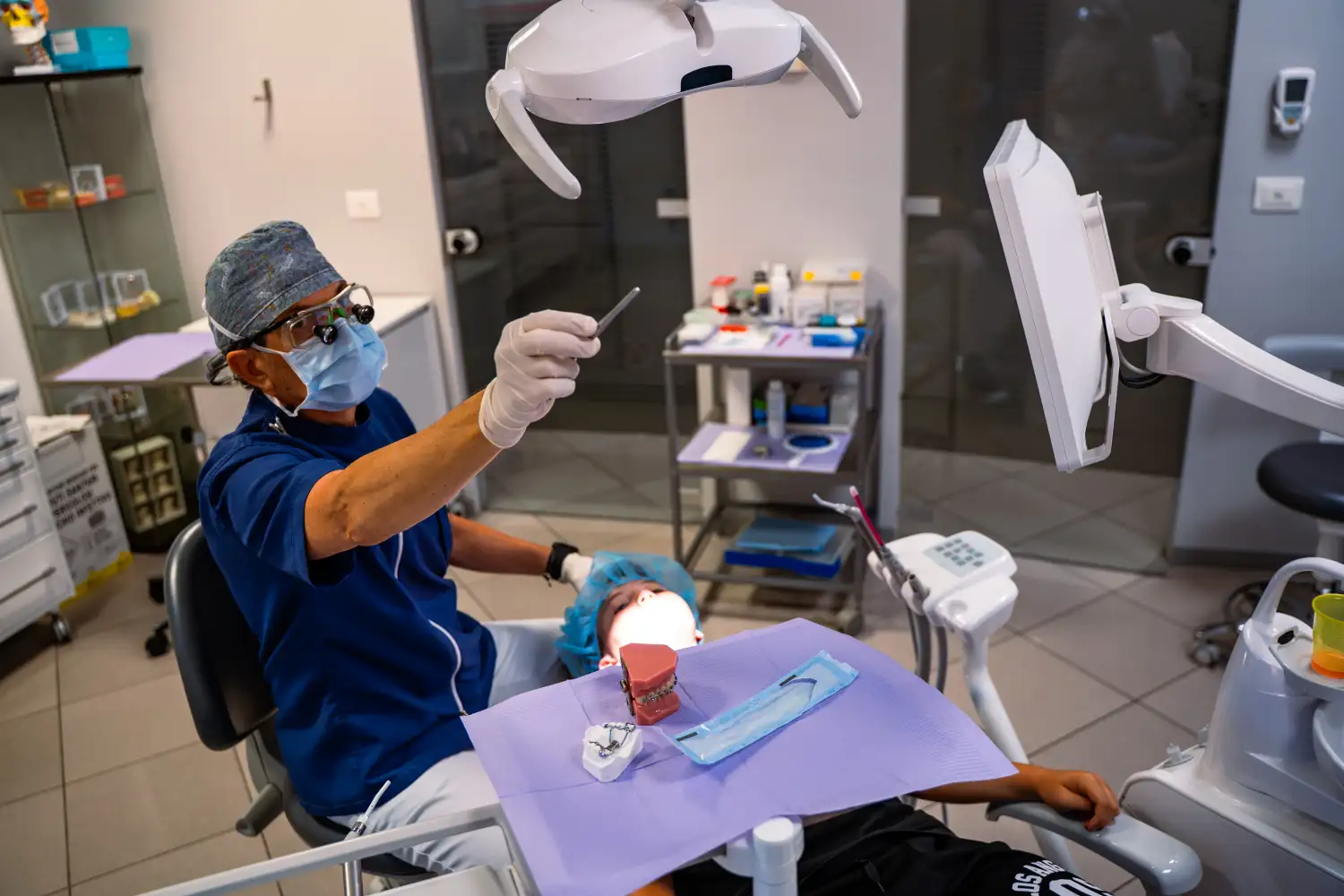 Dentista dello Studio Isaza che visita bambino con luce e specchietto, Bologna