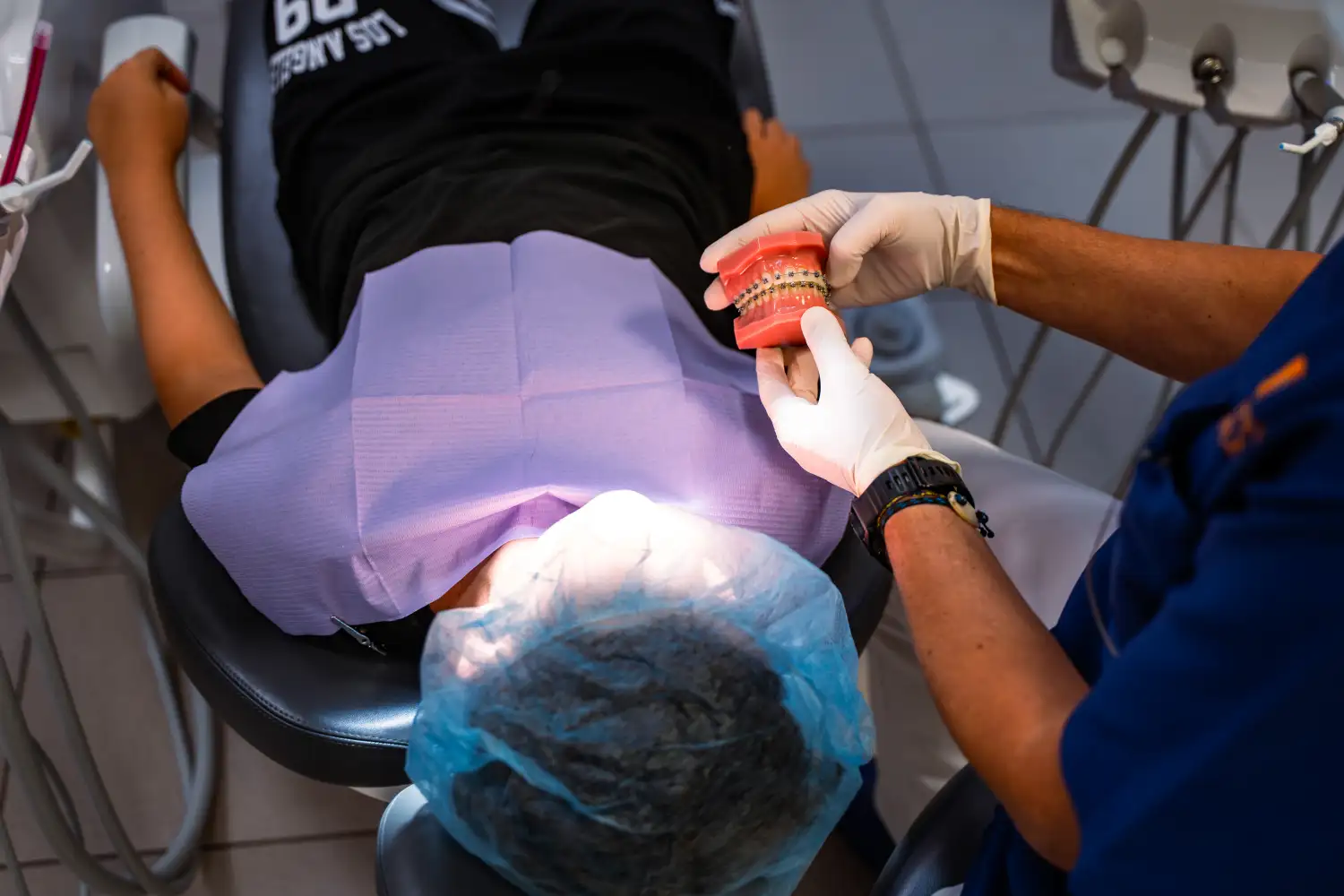 Ortodontista dello Studio Isaza che mostra modello dentale a paziente in poltrona, Bologna