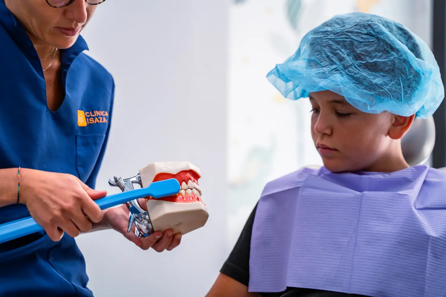 Ortodontista dello Studio Isaza che mostra tecnica di spazzolamento su modello dentale a bambino, Bologna